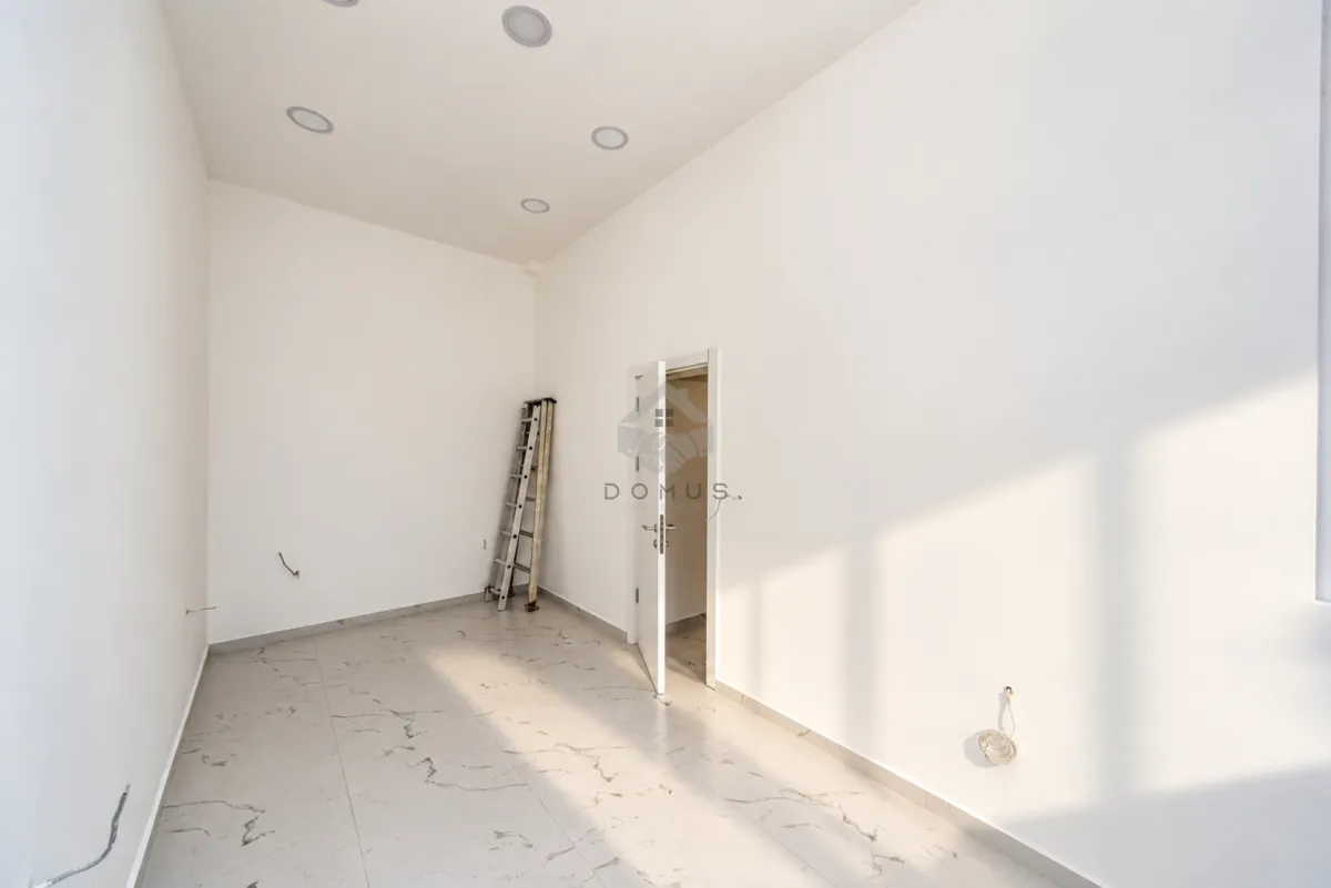 Empty bright room with tiled flooring and an open door.