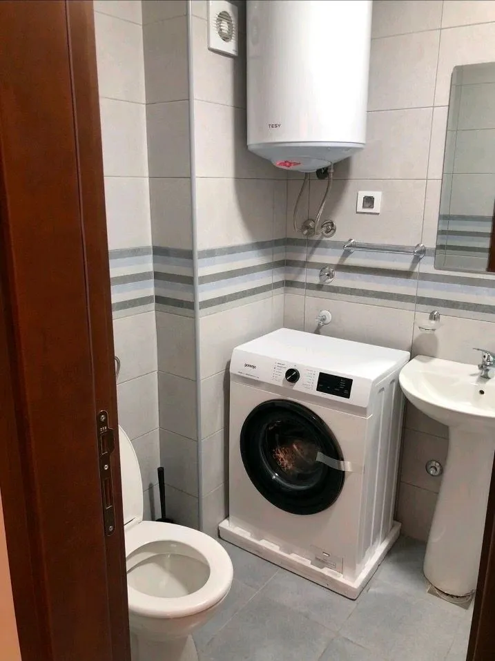 Pogled na opremljeno kupatilo sa veš mašinom, bojlerom i sanitarijama.