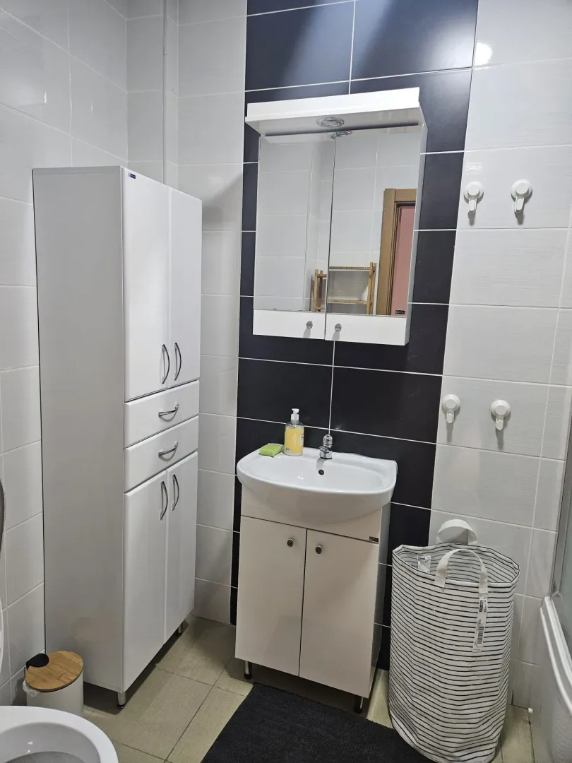 Bathroom equipped with a washbasin, cabinet, mirror, and laundry basket.