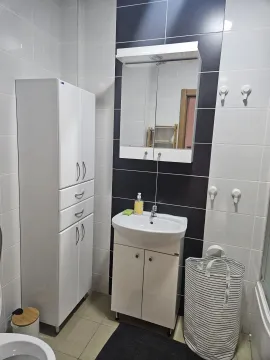 Bathroom equipped with a washbasin, cabinet, mirror, and laundry basket. - image 14