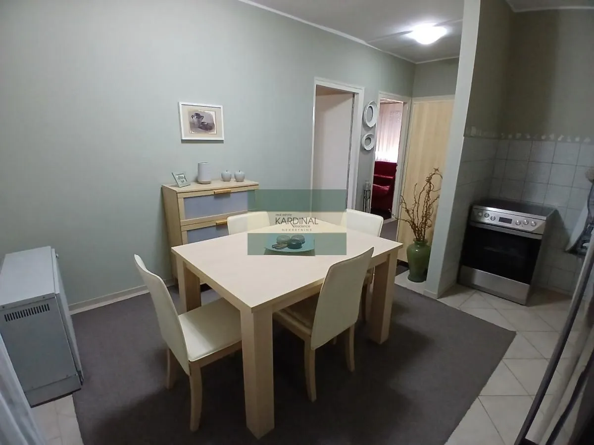 Trpezarija sa stolom, stolicama i komodom u sklopu dnevnog boravka.