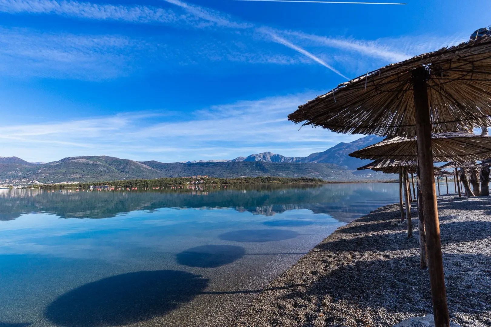 Pogled na more i planine sa plaže sa suncobranima.