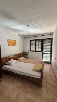 Spavaća soba sa dva drvena kreveta i izlazom na terasu. - image 4