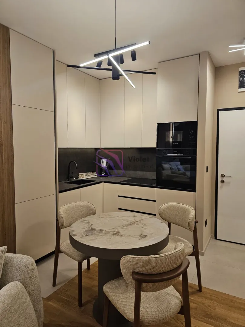 Modern kitchen with built-in appliances and a dining table with four chairs.