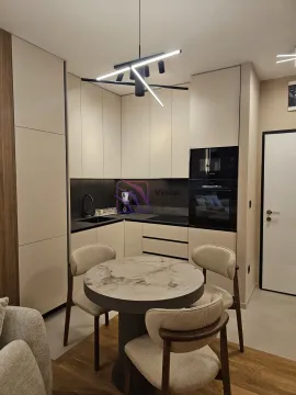 Modern kitchen with built-in appliances and a dining table with four chairs. - image 2