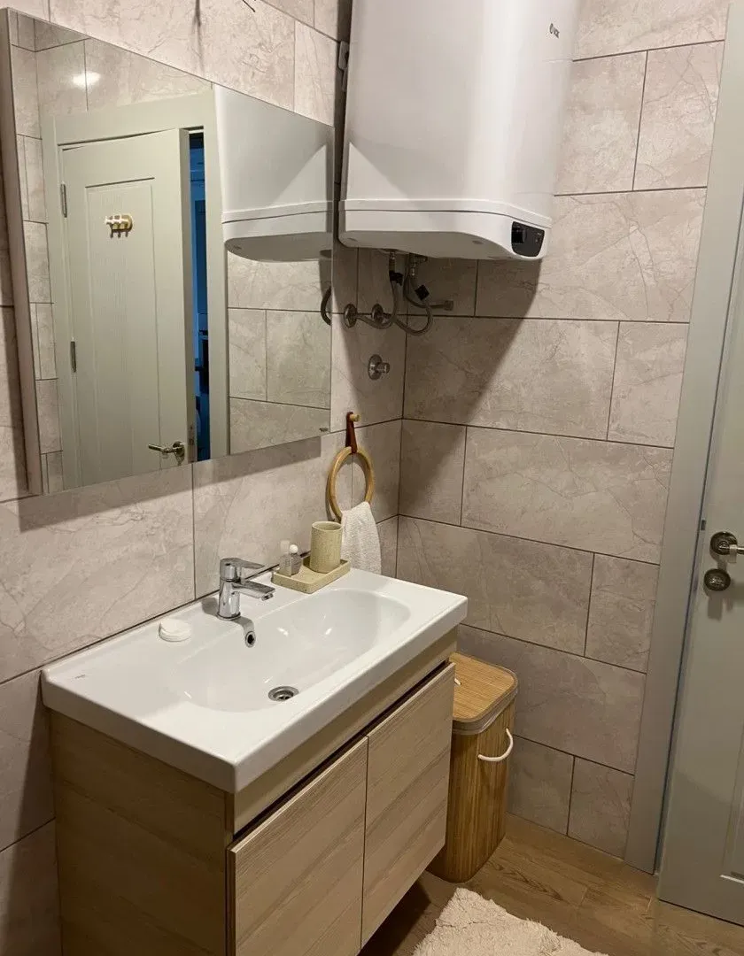 Small bathroom with a sink, mirror, and water heater.