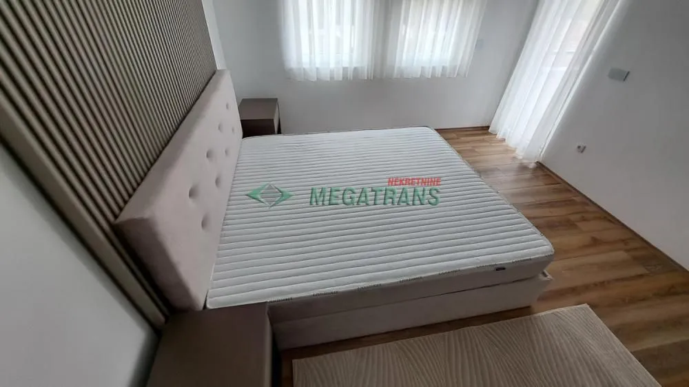 Spavaća soba sa bračnim krevetom i noćnim stočićima.