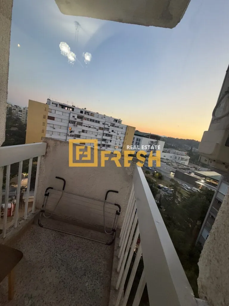 Manji balkon sa ogradom i sušačem za veš, sa pogledom na grad.