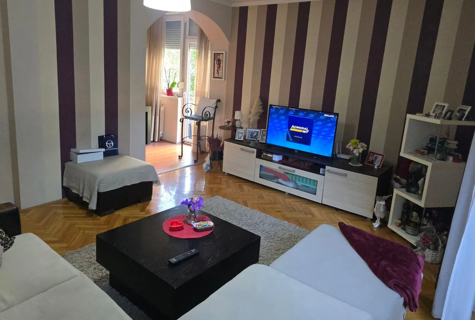 Dnevna soba sa garniturom, TV komodom i parketom na podu.
