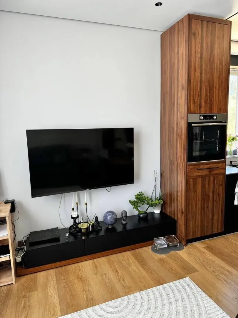 Dnevni boravak sa montiranim TV-om i ugradnim drvenim elementom.