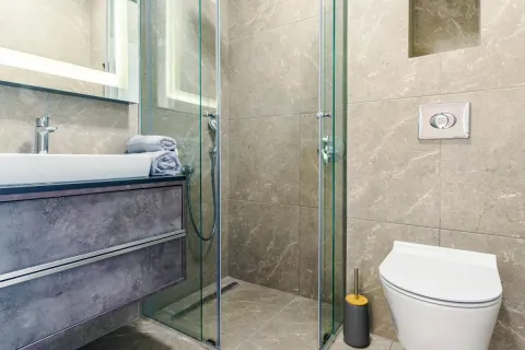 Moderno kupatilo sa staklenom tuš kabinom i elegantnim sivim pločicama. - image 10