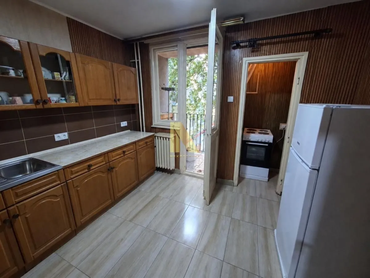 Kitchen with wooden cabinetry, refrigerator, and access to the terrace.