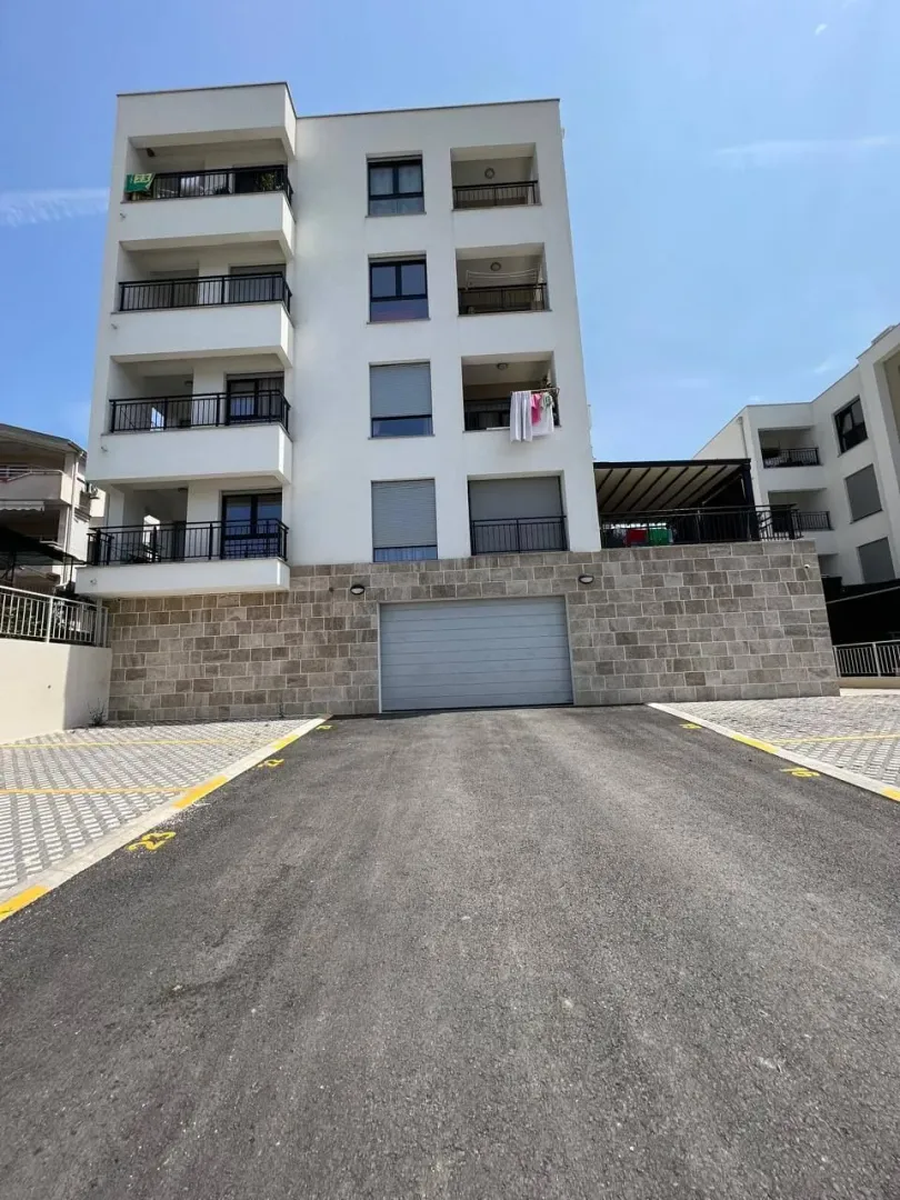 Pogled na fasadu moderne stambene zgrade sa parkingom i garažom.