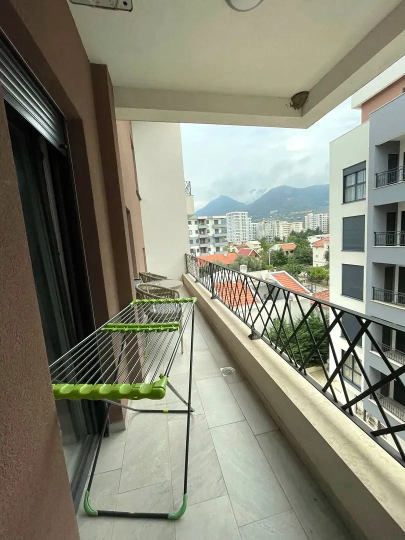 Long balcony with a clothes drying rack and a city view.