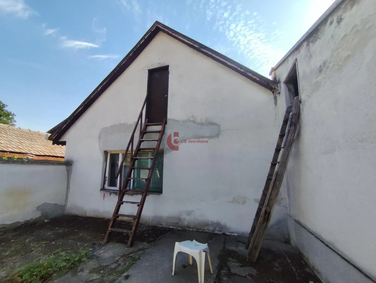 Pogled na spoljašnjost kuće sa spoljnim stepenicama i ulazom na tavan.