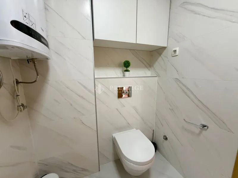 Moderno opremljeno kupatilo sa bijelim keramičkim pločicama i ugradnim elementima.