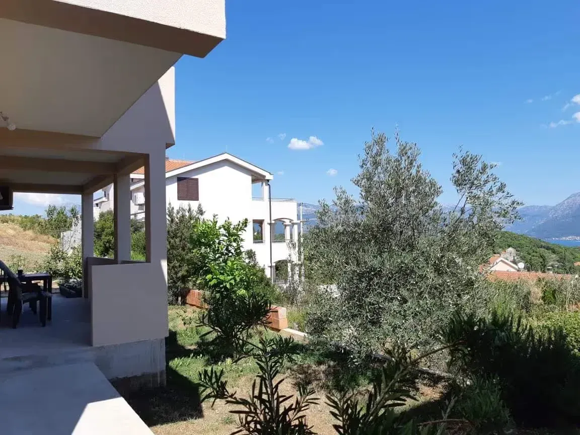 Pogled sa terase i dvorišta na okolne kuće i zelenilo.