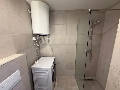 Bathroom with a walk-in shower, water heater, and washing machine. - image 7