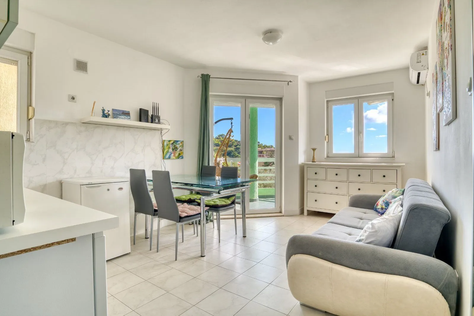 Living room with a sofa, dining area, and access to the terrace.