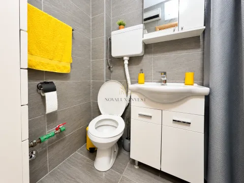 Manje kupatilo obloženo sivim pločicama sa bijelom sanitarijom i žutim detaljima. - image 11
