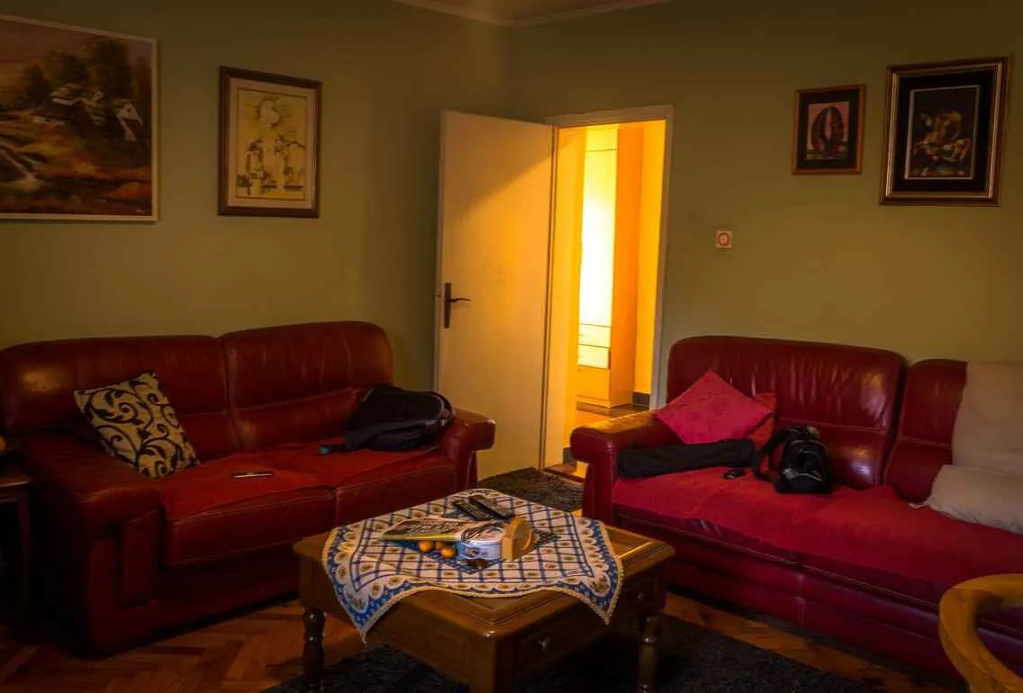 Dnevna soba sa crvenim kožnim garniturama i drvenim stočićem.