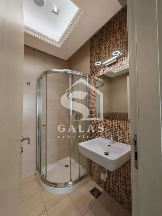 Bathroom equipped with a shower cabin, washbasin, and lighted mirror.