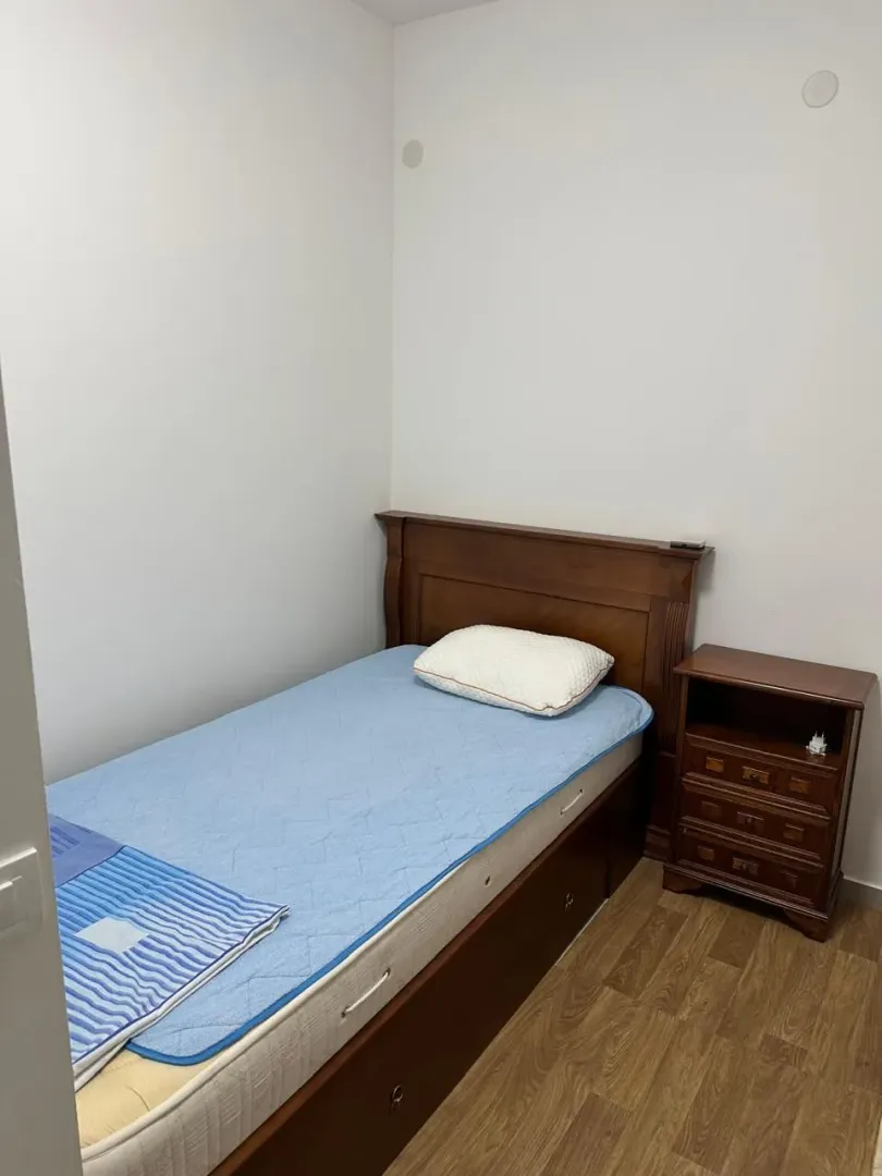 Manja spavaća soba sa krevetom i noćnim ormarićem.