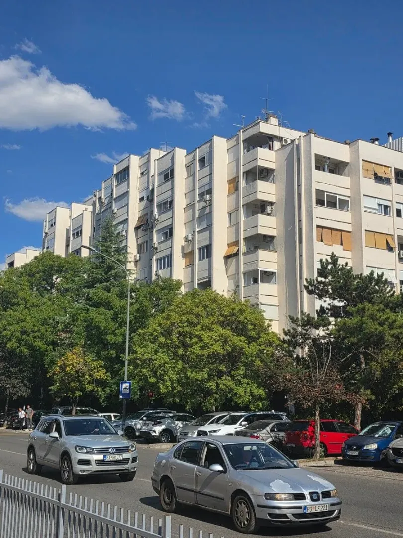 Pogled na spoljašnjost stambene zgrade i ulicu ispred.
