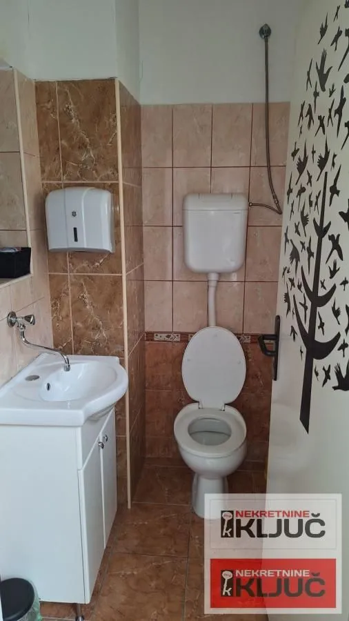 Manje kupatilo sa lavaboom, wc šoljom i zidnim pločicama.