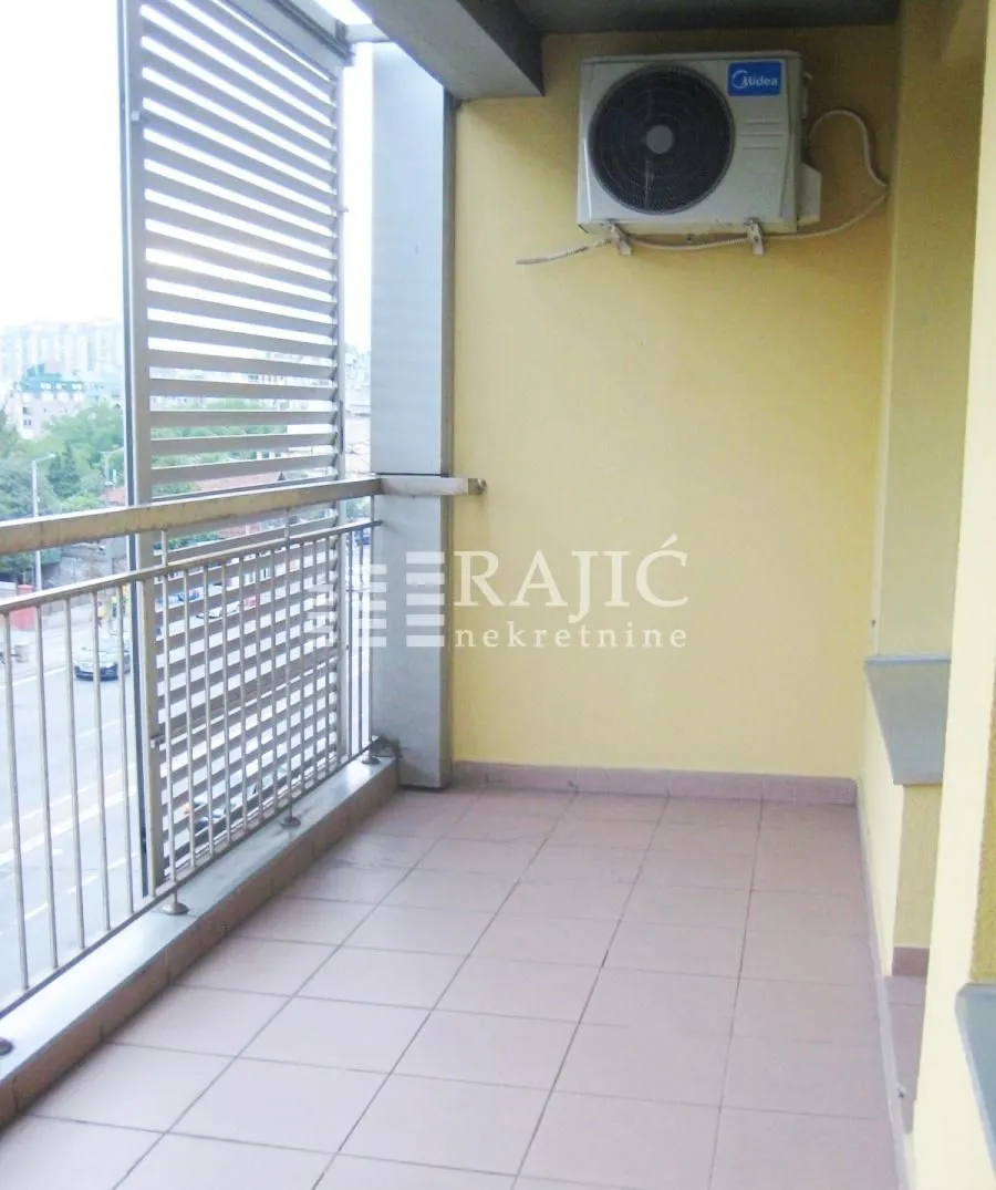 Covered balcony with ceramic tiles and metal railing.