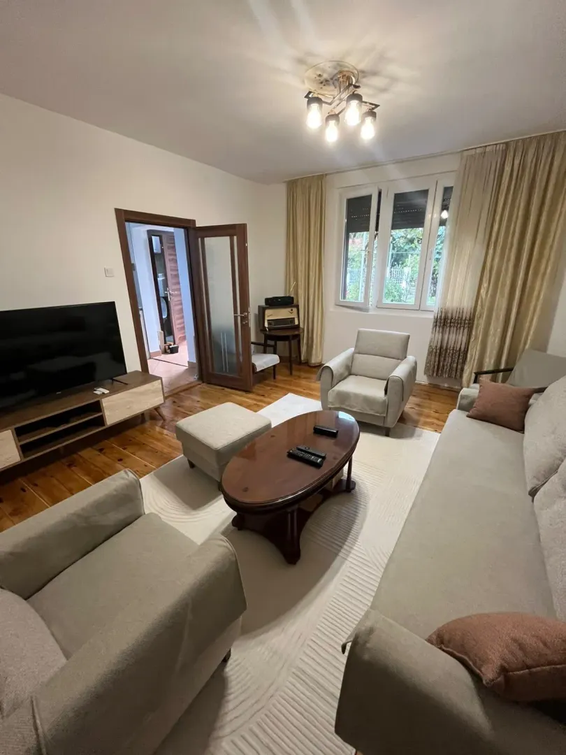 Living room with seating set, TV, and wooden flooring.