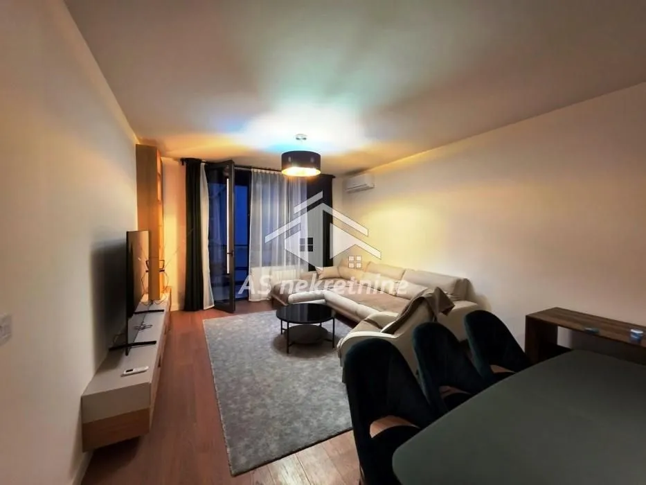 Living room with a sofa, TV, and dining table.