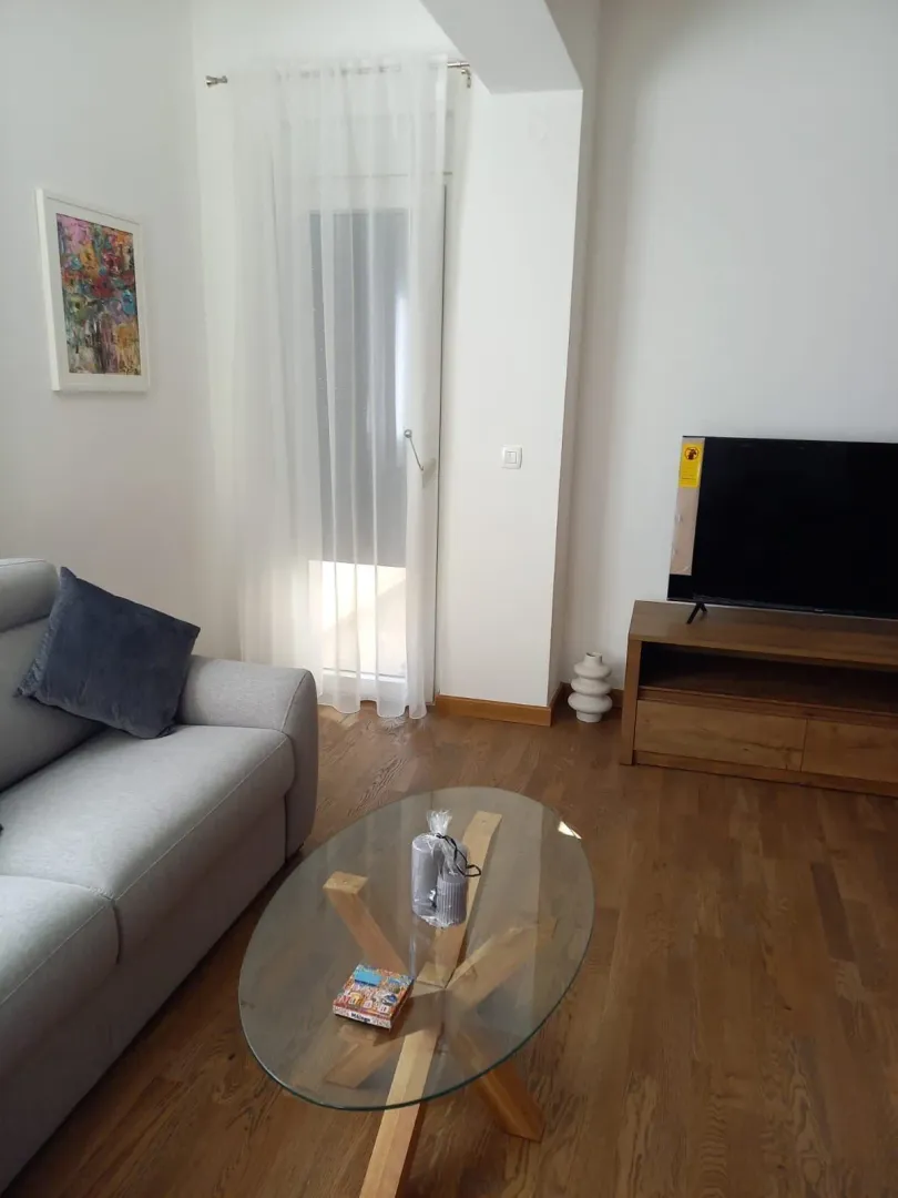 Bright living room with a sofa, TV, and glass coffee table.