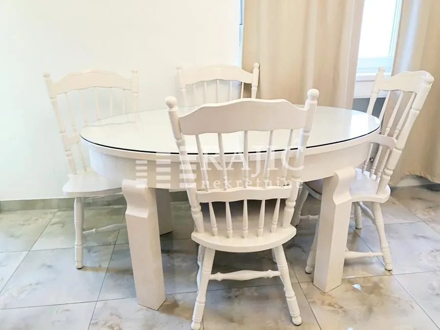 Dining table with white wooden chairs.