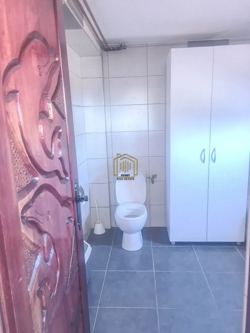 Manje kupatilo sa WC šoljom i bijelim ormarićem.