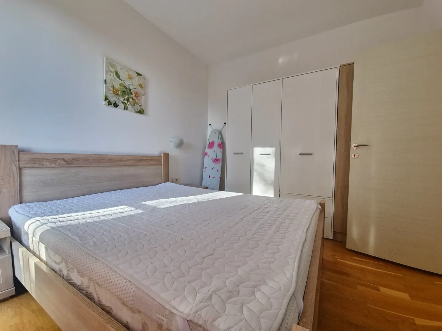 Bedroom with a double bed, wardrobe, and wooden flooring.