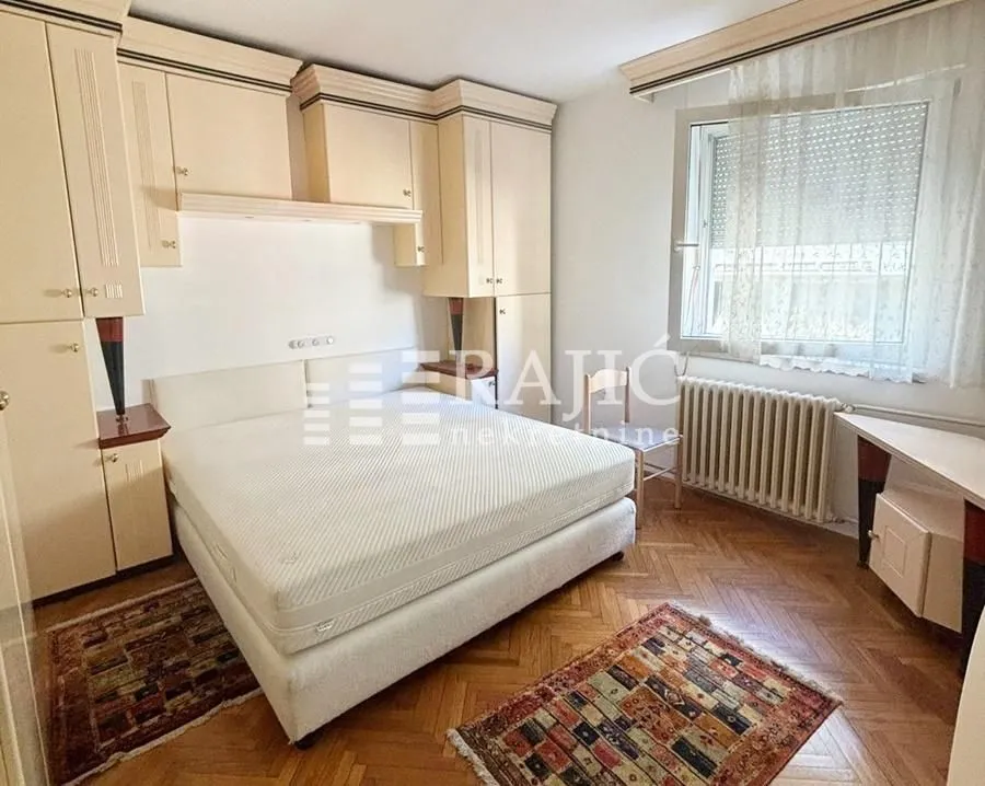 Furnished bedroom with a double bed, built-in wardrobes, and a window.