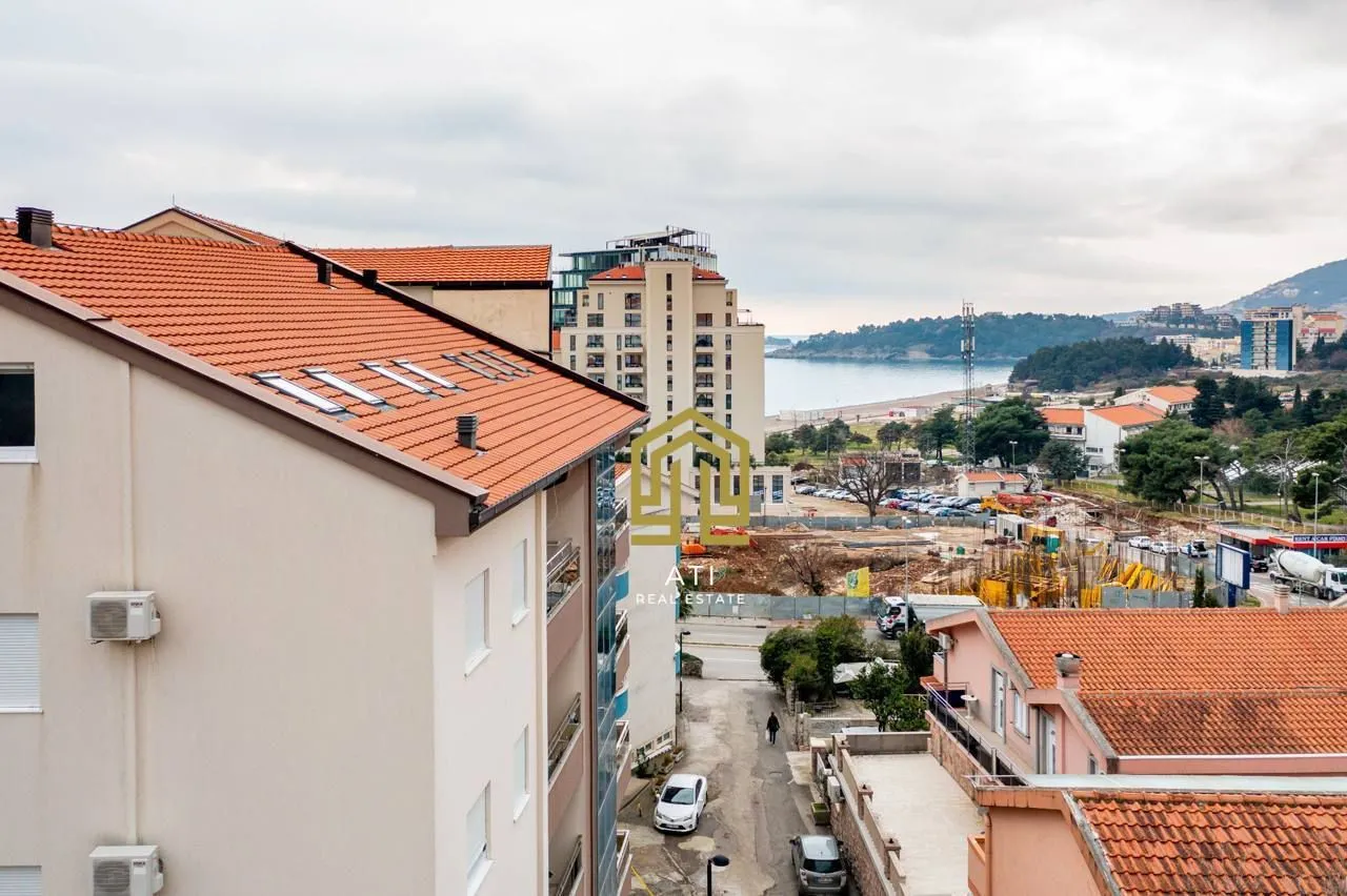 Pogled sa terase na okolne zgrade, gradilište i more u daljini.