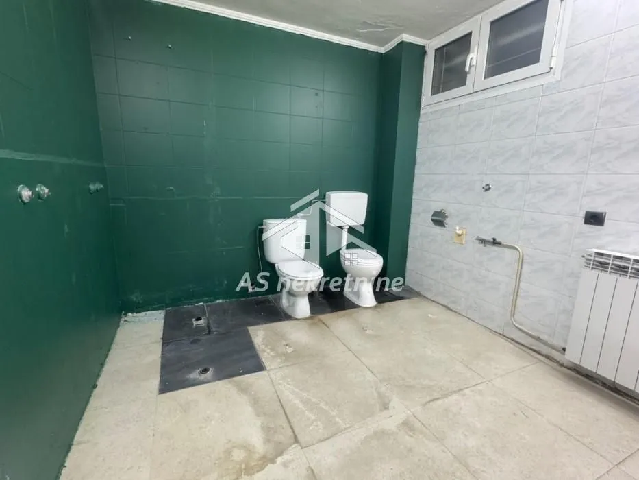 Empty bathroom with tiled walls and two toilets.