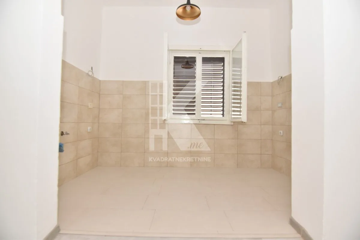 Empty room with ceramic tiles on the wall and floor, and a window.