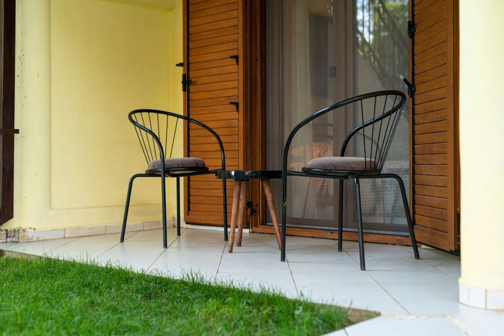 Furnished terrace with two chairs and a small table in front of the apartment entrance.