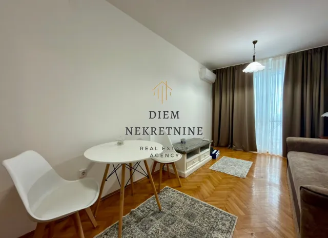 Living room with a dining table, sofa, and parquet flooring.