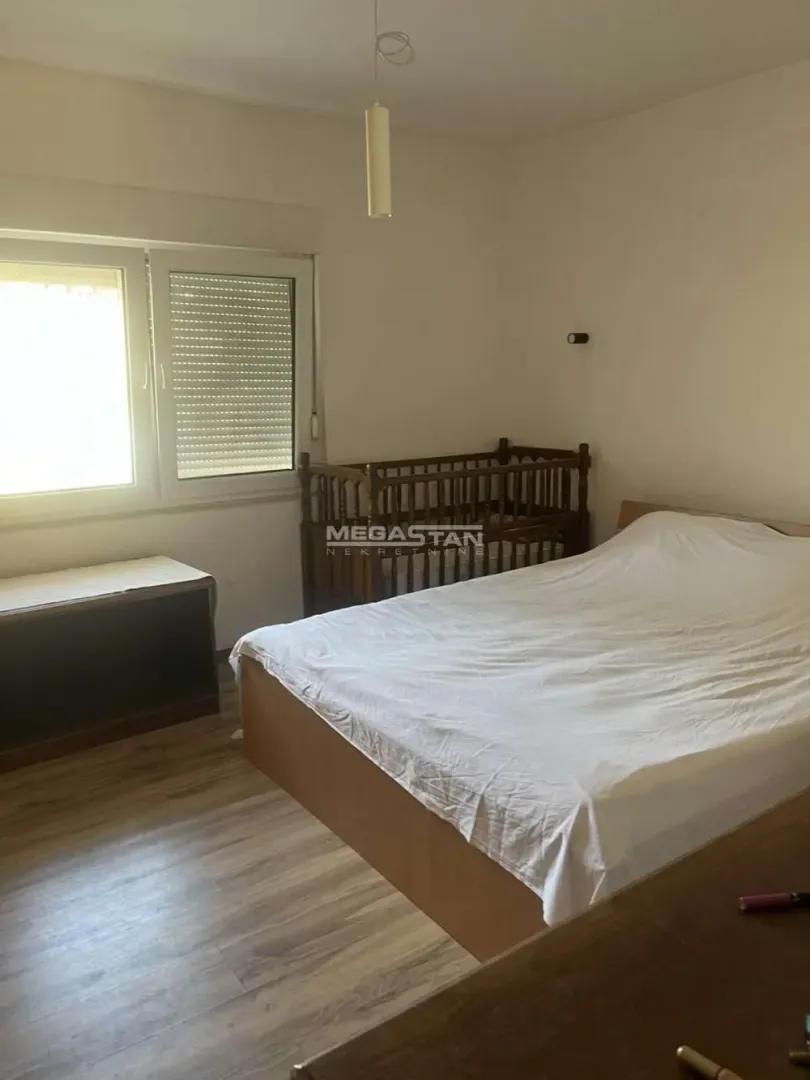 Spavaća soba sa bračnim krevetom, krevetcem za bebe i prozorom.