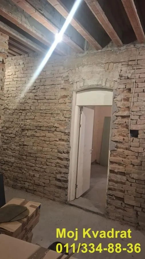 View of a room under renovation with exposed bricks and an open door.