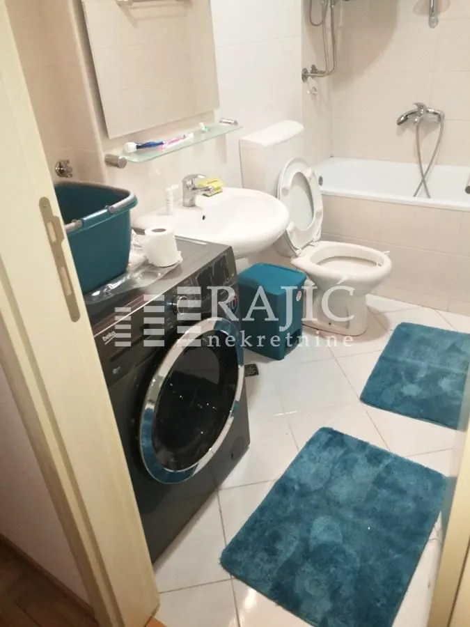 Small bathroom with a bathtub, sink, and washing machine.