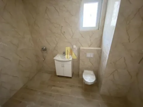 Novoopremljeno kupatilo sa umivaonikom i toaletom u bež pločicama. - image 10