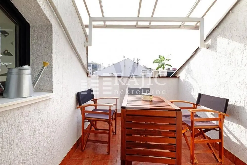 Covered terrace with a wooden table and chairs.