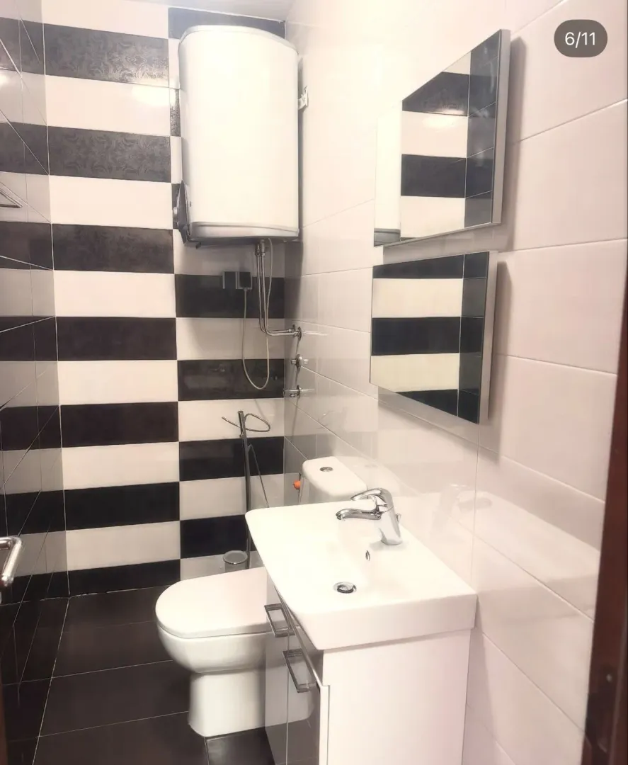 Small bathroom tiled in black and white with a sink and toilet.