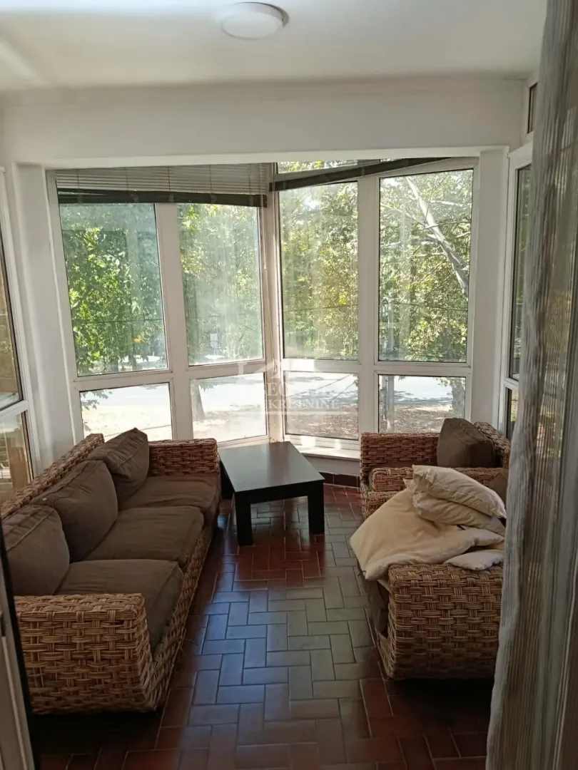 Enclosed terrace with seating furniture and large windows.