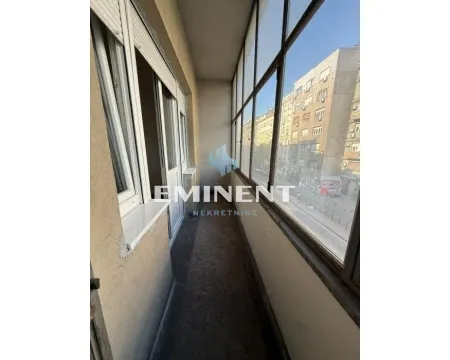 Enclosed balcony with a view of the street and city buildings. - image 13
